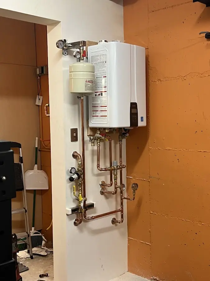 Plumbing technician inspecting water heater connections in Pawling
